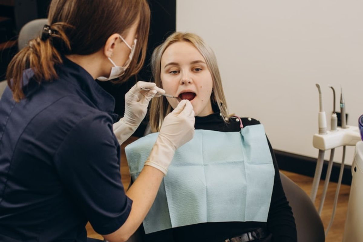 Dental hygienist examining patient's teeth during routine checkup at dental office.