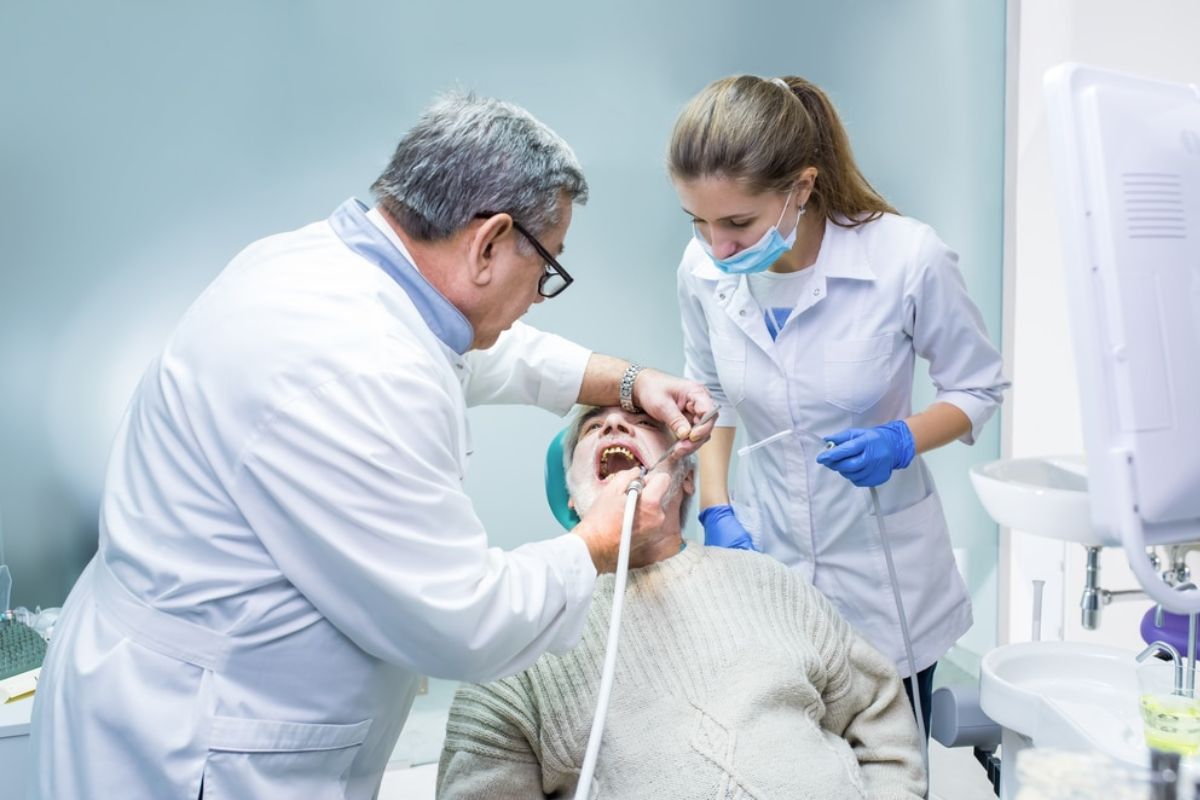 Dentist and dental assistant examining patient's teeth in modern dental office clinic.