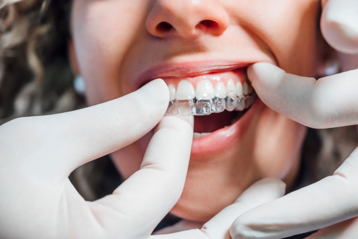 Dentist examining patient's teeth and braces during dental checkup with gloved hands.