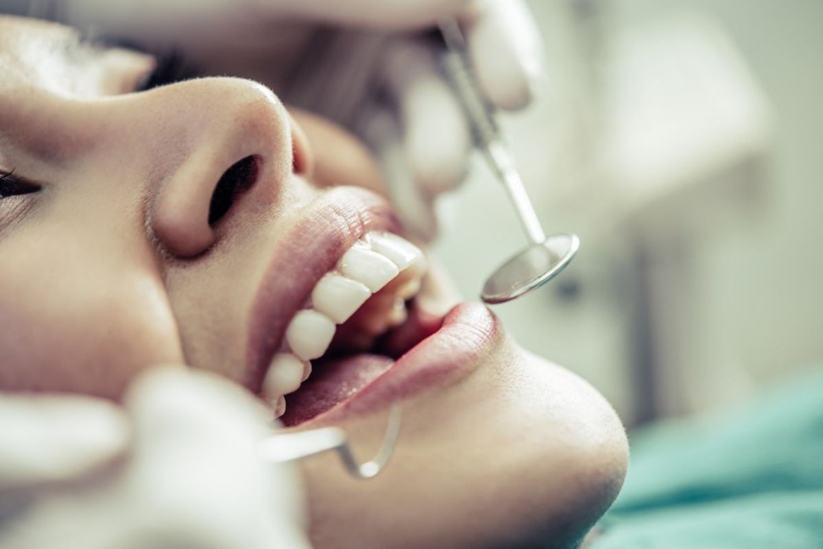 Dentist examining patient's teeth during dental checkup with professional instruments